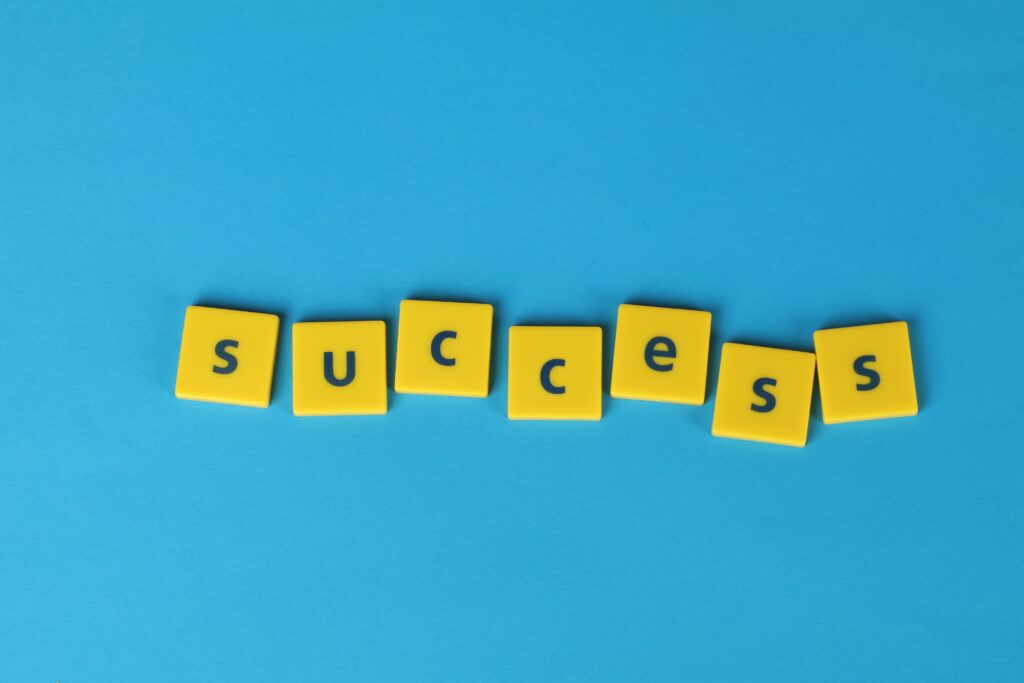 Yellow letter tiles spell the word success on a vibrant blue backdrop, symbolizing achievement.